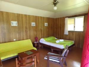 Cette chambre comprend deux lits, une table et des chaises. dans l'établissement Pension Temaeva, à Opoa
