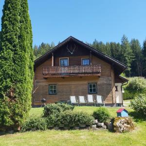 a log house with a deck and chairs on it at Haus Sonnenalm in Forstau