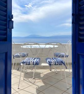 een tafel en stoelen op een balkon met uitzicht op de oceaan bij Vlichos Studio Apartment in Hydra