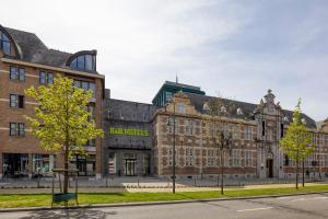 un grand bâtiment en briques avec des arbres devant lui dans l'établissement B&B HOTEL Hasselt, à Hasselt