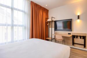 a hotel room with a bed and a flat screen tv at B&B HOTEL Hasselt in Hasselt