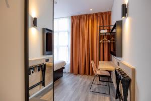 une chambre d'hôtel avec un bureau et une chambre avec un lit dans l'établissement B&B HOTEL Hasselt, à Hasselt