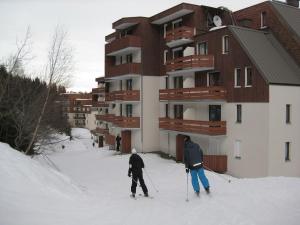 dwoje ludzi na nartach w śniegu przed budynkiem w obiekcie Appartement Le Pleynet, 1 pièce, 3 personnes - FR-1-557A-26 w mieście La Ferrière