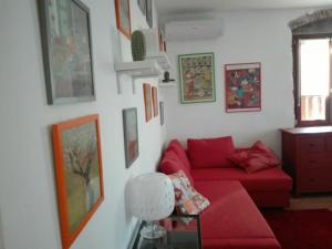 a living room with a red couch and pictures on the wall at Veronauptoyou Apartments in Verona