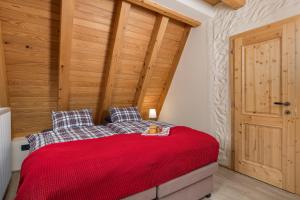 a bedroom with a red bed with a wooden wall at Mountain house Beauty of Laz in Ravna Gora