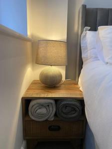 a nightstand with a lamp and towels on it next to a bed at Brand New Property - Bradford City Centre in Bradford