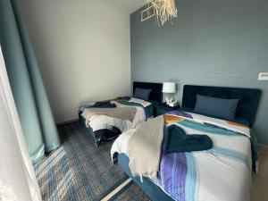 two beds in a room with blue walls at Relaxing villa with access to pool and beach in Ras al Khaimah