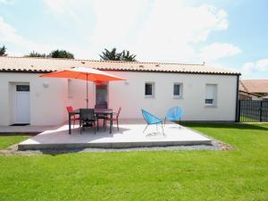 a patio with a table and chairs and an umbrella at Gîte au calme avec jardin privé, vélos gratuits, équipements bébé et garage - proche de Nantes et plages - FR-1-306-980 in Saint-Philbert-de-Grand-Lieu