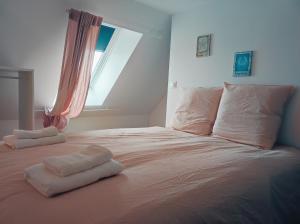 een bed met twee handdoeken en een raam bij Superbe appartement neuf à Barneville Plage in Barneville-Carteret