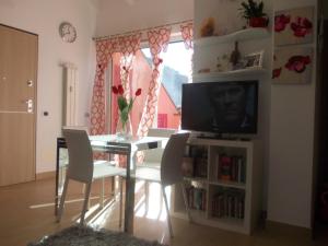 - un salon avec une télévision, une table et des chaises dans l'établissement A casa di Laura Finale Ligure, à Finale Ligure