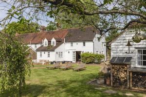 a large white house with benches in the yard at Cosy Cottage with Beautiful Garden, HotTub & Sauna in Marden