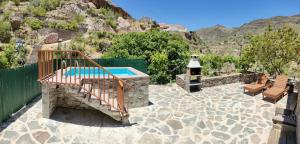 a patio with a swimming pool and two benches at Casita el Parral in Tejeda