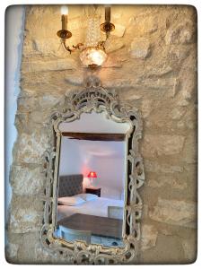 un miroir suspendu à un mur en pierre avec un lit dans l'établissement La Providence, à Apt