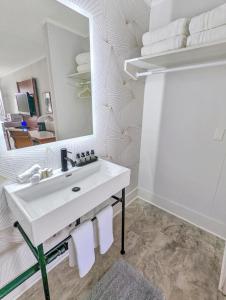 Baño blanco con lavabo y espejo en The Inn On Main en Chincoteague