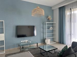 a living room with a flat screen tv on a blue wall at Relaxing villa with access to pool and beach in Ras al Khaimah