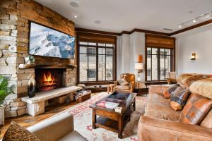 a living room with a fireplace and a stone wall at Arrowleaf Lodge - 3 Bed Condo #302 in Park City
