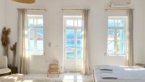 a white bedroom with a bed and two windows at Townhouse Christos in Panormos Skopelos