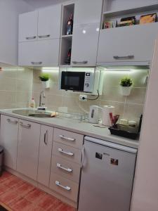 a kitchen with white cabinets and a sink and a microwave at Apartman Temida Lux in Vrnjačka Banja