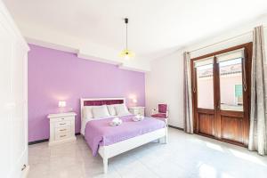 a bedroom with purple walls and a bed and a window at Affittacamere Nonno Natalino in Castelsardo