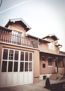 a house with white garage doors and a balcony at Royal TSV Rooms in Sombor