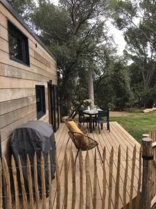 une terrasse en bois avec une table, des chaises et une clôture dans l'établissement TINY HOUSE LA FARIGOULE, à Pélissanne