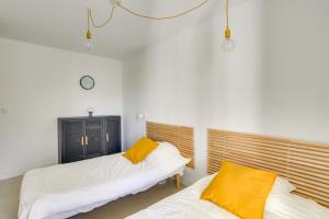 Cette chambre comprend 2 lits avec des murs blancs et des oreillers jaunes. dans l'établissement "Le Massilia" Beau duplex avec balcon à Marseille, à Marseille
