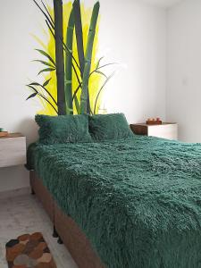 - une chambre avec un lit doté d'une couverture verte et d'une plante dans l'établissement Cálido apartaestudio en La Castellana, à Armenia