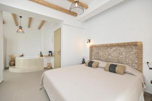 a white bedroom with a bed and a bath tub at Naxos Blue Sky in Naxos Chora