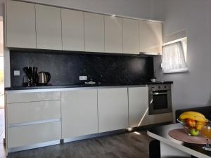 une cuisine avec des placards blancs et un comptoir noir dans l'établissement Apartmani Rudi, à Anić
