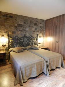 a bedroom with a large bed and a stone wall at Hotel Rural La Casa del Peregrino in El Acebo de San Miguel