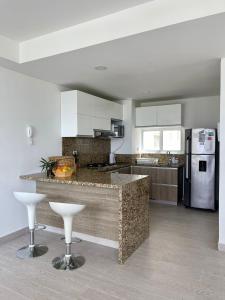 a kitchen with a counter and some stools in it at CONDOMINIO ZAZUE, SANTA MARTA, PLAYA BELLO HORIZONTE wifiiiii in Santa Marta