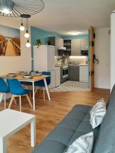 uma sala de estar e cozinha com uma mesa e um sofá em Joli 2 pièces sur le port avec piscine, terrasse, parking em Capbreton