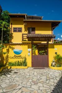 a yellow house with a gate in front of it at Pousada Cachadaço in Trindade