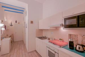 Biała kuchnia ze zlewem i kuchenką mikrofalową w obiekcie Approdo Rooms - Eja Sardinia w Cagliari