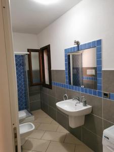 een badkamer met een wastafel, een toilet en een spiegel bij RESIDENZA SARDINIA OROSEI in Orosei