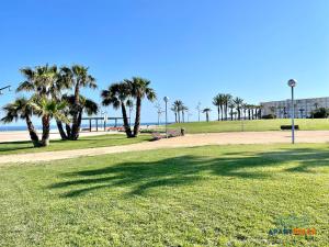 een park met palmbomen en het strand bij APARTBEACH NOVA PINEDA con PARKING Y CLIMA in La Pineda