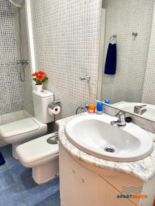 een badkamer met een wastafel, een toilet en een spiegel bij APARTBEACH NOVA PINEDA con PARKING Y CLIMA in La Pineda