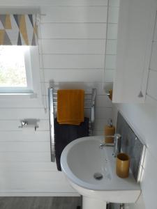 a white bathroom with a sink and a window at Delightful cosy cabin in Margate