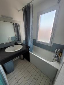 a bathroom with a sink and a tub and a window at Rêves Salés in Mimizan