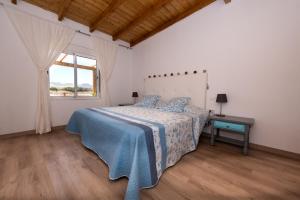 a bedroom with a bed with a blue blanket and a window at Los Olivos in Cardón