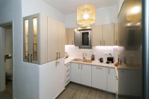 a kitchen with white cabinets and a sink at Cycladic Home on the hill with beautiful views!! in Agkidia