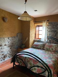 a bedroom with a bed with a stone wall at Luar no Xurés in Bubaces