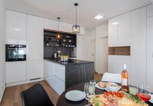 uma cozinha com armários brancos e uma mesa com copos de vinho em Apartment Mia Šimuni em Simuni