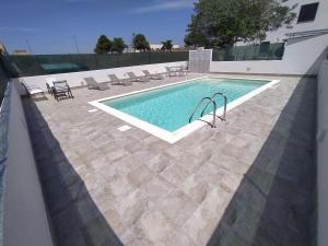 TriscinaにあるAPPARTAMENTO CON 3 CAMERE CON BAGNO INTERNO, CUCINA Sea & Sun 3のスイミングプール(椅子、テーブル付)