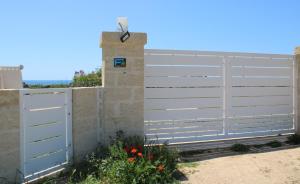 a white privacy fence with a gate and a wall at Perla delle Maldive in Marina di Pescoluse