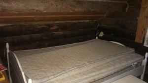 uma pequena cama na parte de trás de um quarto em Könölä em Outokumpu