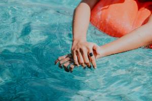 een vrouw in een zwembad met haar hand in het water bij The Inn On Main in Chincoteague