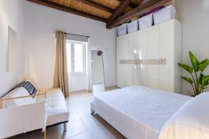a white bedroom with a bed and a couch at Castello Attic Sunset in Cagliari +2 photos