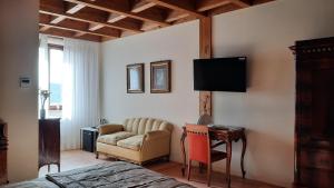 een slaapkamer met een bank en een tv aan de muur bij Palazzo Laureano - Dimora Storica in Tricarico