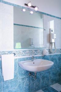 a white sink sitting under a mirror in a bathroom at Hotel Ambassador in Grottammare